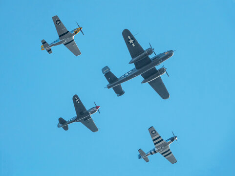 American WWII Military Aircraft Flying in Formation, including a B-25 bomber, P-51 Mustangs and a P-40 Warhawk.