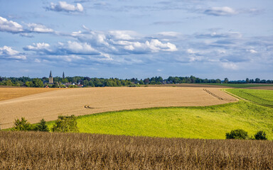 the two churches called Wiesnasen of Ratingen Homberg at summer sun with wheat field and lush green meadow at blue cloudy sky