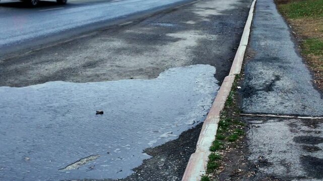 empty street reflections, worn pavement mirrors sky scene, damaged curbside reflects tranquil sky view, faded street edge with reflective puddle suggests neglect and need for maintenance