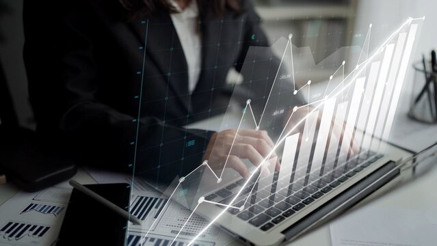A business professional engages in data analysis on a laptop, showcasing growth trends through a graphical overlay in a modern office setting for financial insights. Copula