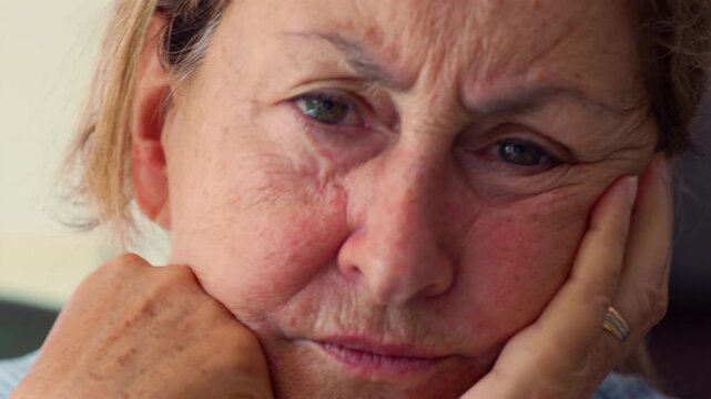 Elderly woman resting her head on hand, suspicious expression showing doubt and unease, intimate close up portrait of aging, emotion, and human introspection