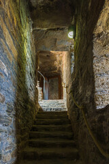 A narrow and dark stone staircase leading upwards inside an ancient medieval castle (Conwy, Wales, United Kingdom)
