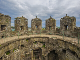 The ancient stone battlements on the rooftop of a medieval castle tower ruin (Conwy, Wales, United Kingdom)