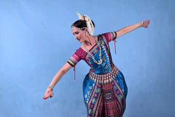 Indian dancer in the studio on a blue background in a dance pose