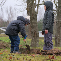 Siblings Using a Small Shovel or Scoop as a Lever to Adjust the Position of a Large Stone in the Fort Wall