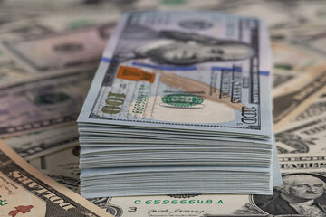 Close Up Stack of New One Hundred US Dollar Bills on Scattered Money Background