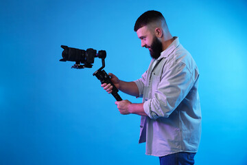 Videographer using gimbal stabilizer with camera on light blue background