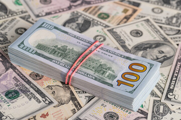 Close Up Stack of New One Hundred US Dollar Bills on Scattered Money Background