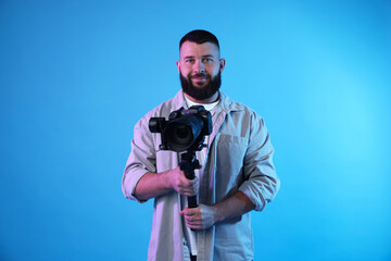 Obraz premium Videographer using gimbal stabilizer with camera on light blue background