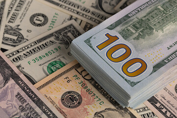 Close Up Stack of New One Hundred US Dollar Bills on Scattered Money Background