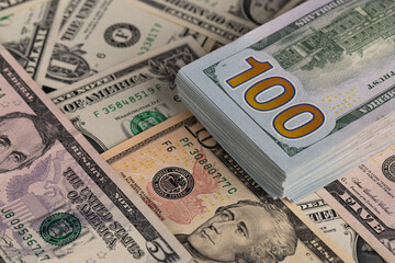 Close Up Stack of New One Hundred US Dollar Bills on Scattered Money Background