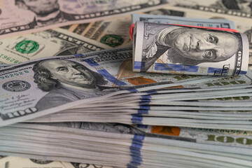 Close Up Stack of New One Hundred US Dollar Bills on Scattered Money Background