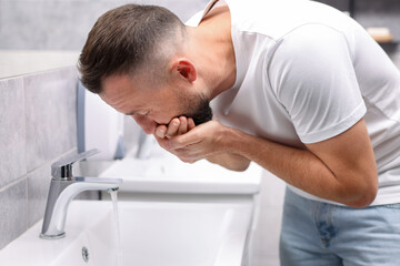 Fototapeta premium Man suffering from nausea over sink in bathroom