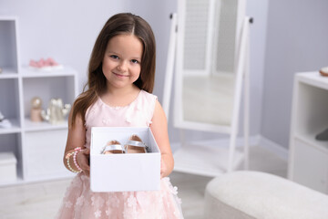 Little girl with pair of beautiful shoes in box at shop. Space for text