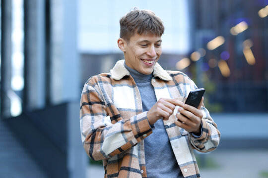 Smiling man in shirt with smartphone on city street