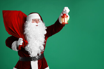 Santa Claus with red bag of Christmas gifts and lantern on green background, space for text