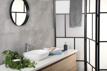 Stylish bathroom interior with mirror, folding screen and vessel sink