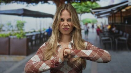 Blonde woman tightly clenches hands into fists on sidewalk during morning rush; anger frustration...