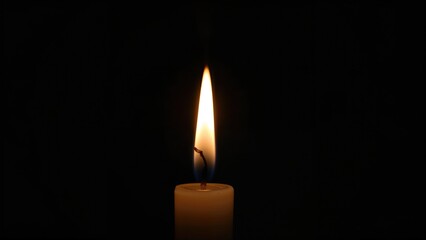 A single candle flame in darkness with minimal lighting. Light and illumination concept. The image of a lit candle in a dark environment.
