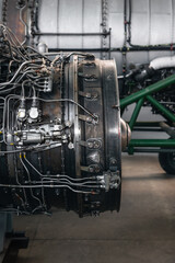 Airplane engine maintenance. Side view of old jet engine without cowling on a stand, another bigger engine in the background.