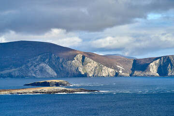 View over the ocean in cloudy blue sky weather with Achill island, Keel vilage and beach