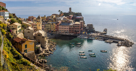 High panoramic view of Vernazza from the trail to Monterosso al Mare, showing the entire village perched on the rocks and the horseshoe-shaped harbor. Cinque Terre, Italy
