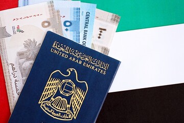 United Arab Emirates dirham currency money bills and passport lies on flag close up. The concept of travel and vacation