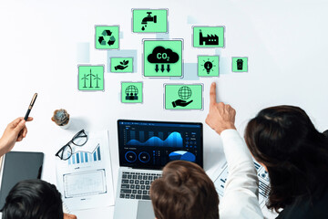 A diverse business team focuses on environmental data displayed on laptops and tablets, highlighting sustainability metrics and collaboration in innovative settings. Trope