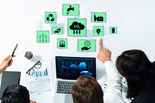 A diverse business team focuses on environmental data displayed on laptops and tablets, highlighting sustainability metrics and collaboration in innovative settings. Trope