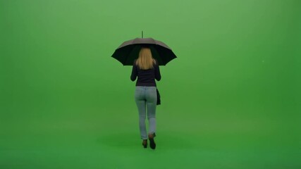 Rear view of a woman walking away with a black umbrella against a green screen background.