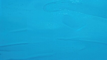 Bright blue textured surface with subtle brush strokes and patterns.