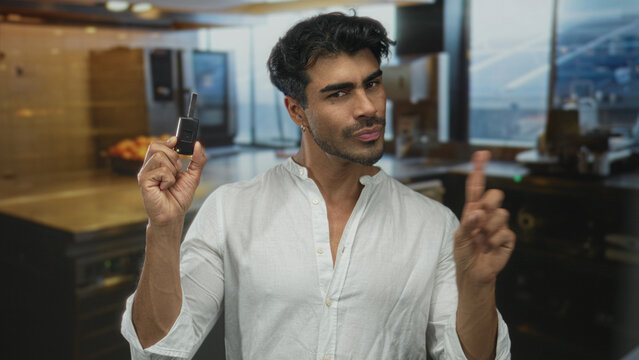 Man holds key fob remote and points finger upward inside kitchen building; confidence assurance success determination.