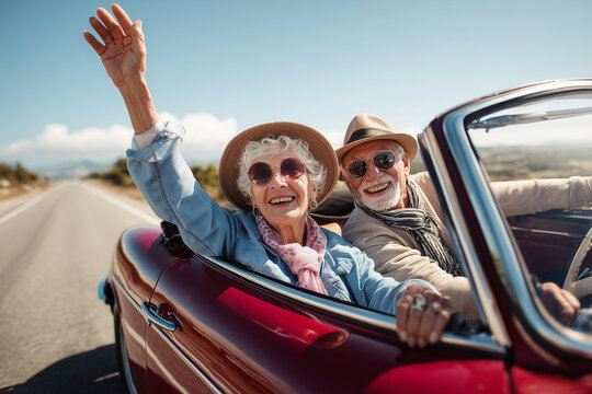 A couple in a red convertible car waving to the camera