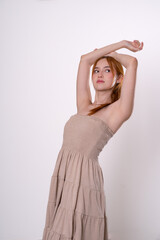Fototapeta premium Red-haired woman posing with raised arms and bright smile, confident studio portrait.
