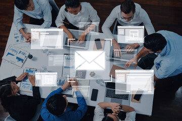 A diverse team collaborates in a modern office setting with various devices and business documents, emphasizing digital communication and strategic planning. Trope