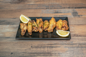 Asian-style fried chicken wings with a ginger, lime, and soy sauce glaze, garnished with chopped peanuts and fresh cilantro leaves
