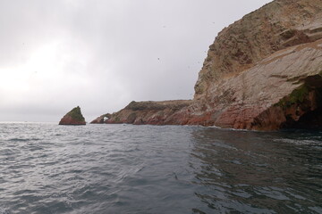 Steep cliffs inhabited by seabirds - seagulls, pelicans in the ocean in Paracas National Park