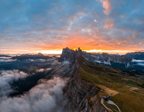 Aerial view of spectacular sunrise at the Seceda mountain ridge line in the Italian Dolomites cloud inversion and golden light - Powered by Adobe