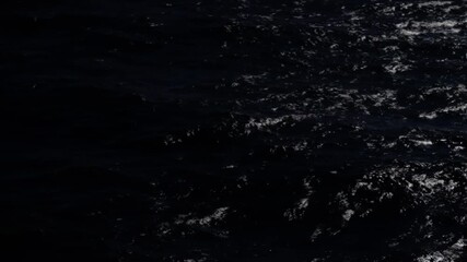 From shadowed depths to sunlit shimmer, an ocean surface shifts from near-black swells to glittering, textured waves as light exposes ripples, foam, and reflective patterns. - Powered by Adobe