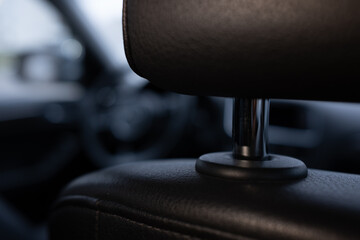 Close-up of a modern car's black leather headrest. Focus on texture and detail with a blurred background. Concept of luxury, comfort, and automotive design.