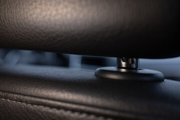 Close-up of a modern car's black leather headrest. Focus on texture and detail with a blurred background. Concept of luxury, comfort, and automotive design.