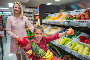 Mother daughter grocery shopping for healthy fresh fruit
