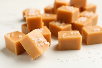Tasty caramel candies with salt on light table, closeup
