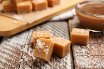 Tasty candies with salt and caramel sauce on color wooden table, closeup