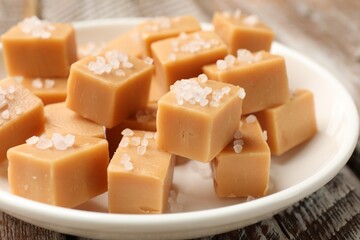 Tasty caramel candies with salt on color wooden table, closeup