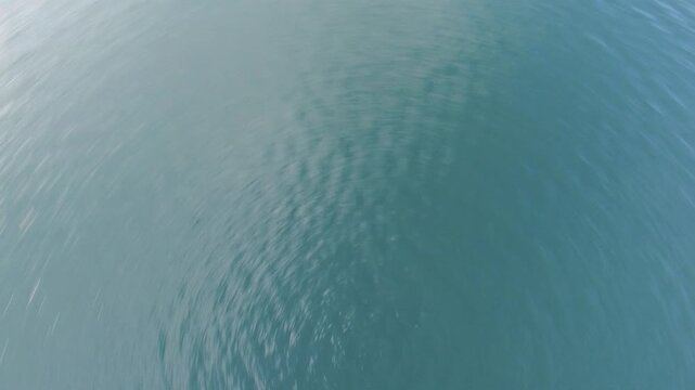 An aerial view captures a body of water spiraling violently, as if seen from a plunging airplane, creating a dizzying vortex where sky and ocean collide in a dramatic, chaotic spin.