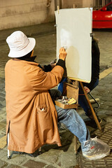 Mujer pintando un retrato al carboncillo en la calle.