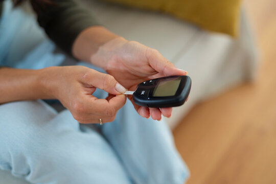 Close-up of a woman inserting a test strip into a glucose meter to measure blood sugar levels.
