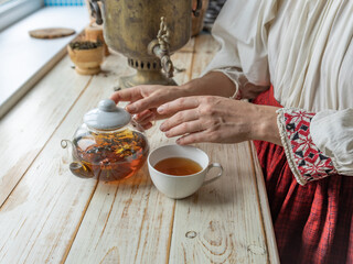 Woman is pouring tea into a cup from a teapot