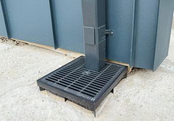 Plastic rainwater gully with grate on concrete base